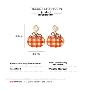 Detailed view of pumpkin earrings with orange checkers, red bow and pearl accents