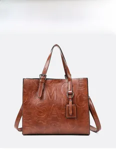 Gros plan détaillé d'un sac cabas marron caramel avec lettres embossées et cuir texturé