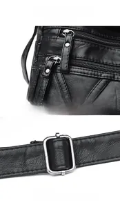 Detail view of smooth silver metal zippers and adjustable buckle on black pebbled leather bag
