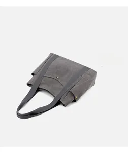 Dettaglio ravvicinato della borsa tote in tela grigia con tasche laterali e trama di tessuto