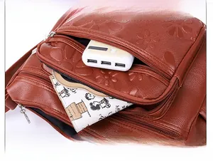 Détail du sac bandoulière en cuir PU marron avec texture florale et poches zippées