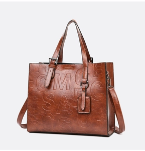 Détail d'un sac cabas marron rétro avec lettres embossées et texture en cuir PU poli