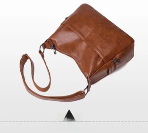 Detailed close-up of brown PU leather shoulder bag with metallic zippers and fine texture