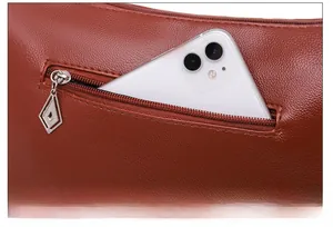 Détail de la poche arrière antivol sur le sac bandoulière en cuir marron grainé