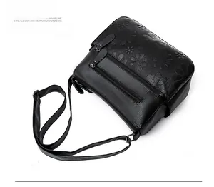 Detail of black embossed leather shoulder bag showing multiple zippers and texture
