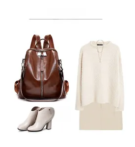Brown vintage leather backpack styled with a beige cable knit sweater and ankle boots