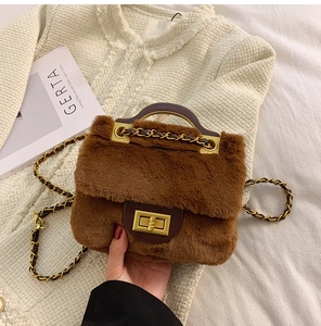 Détail d'un sac bandoulière en peluche marron avec boucle dorée et chaînette