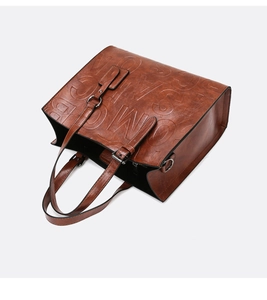 Vue macro du sac cabas marron vintage avec lettres embossées et boucles métalliques