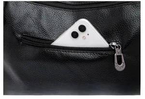 Detail of the back anti-theft zipper pocket on a black litchi grain leather shoulder bag