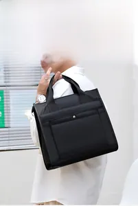 Business casual black nylon laptop bag with shoulder strap worn by a model in daylight