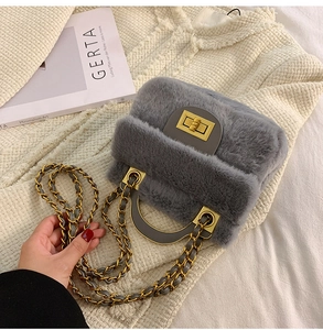 Détail du sac à main gris en peluche avec fermoir doré et bandoulière en chaîne sur tricot