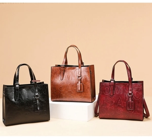Trois sacs cabas élégants en cuir avec lettres embossées en noir, marron et bordeaux chic