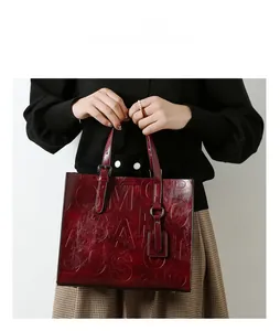 Détail du sac cabas rouge foncé avec lettrage en relief et texture en cuir brillant