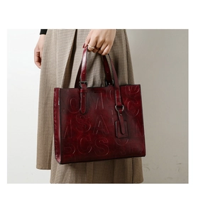 Détail d'un sac cabas bordeaux vintage avec motif alphabet embossé et finition brillante
