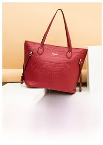 Detailed view of red crocodile pattern tote bag with gold hardware and logo branding