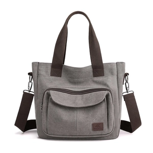 Grey canvas tote bag with brown straps and front zipper pocket for daily commute