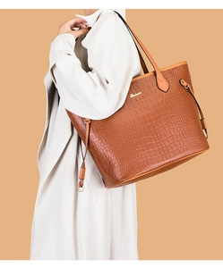 Detail of crocodile pattern texture on brown tote bag with gold Balade metallic logo