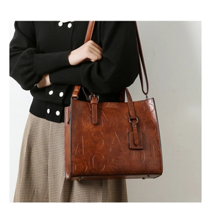 Détail du sac cabas rétro en cuir marron avec lettres embossées et bandoulière