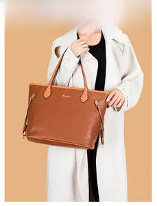 Detailed view of dark brown crocodile pattern tote bag with gold logo on model