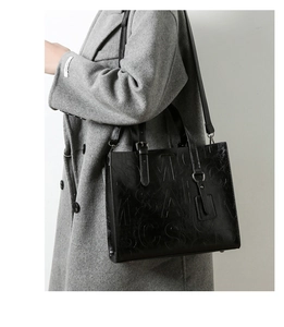 Détail du sac cabas en cuir noir gaufré avec boucles métalliques et bandoulière réglable