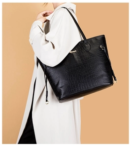 Close-up of black crocodile pattern tote bag with golden logo and drawstring detail