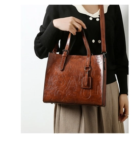 Détail d'un cabas marron vintage avec lettres embossées et texture en cuir poli