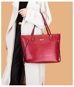 Close-up of red crocodile pattern tote bag with gold metal logo and handle details