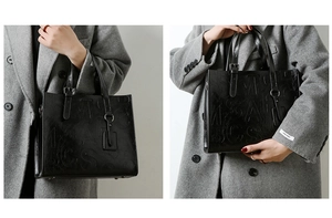 Détail d'un sac cabas vintage en cuir noir avec lettres embossées et doubles poignées