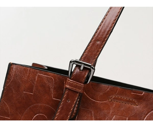 Détail d'un sac à main marron en cuir gaufré avec texture vintage et boucle en métal noir