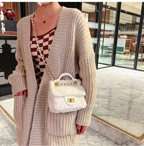 Détail du sac bandoulière en peluche blanche avec fermoir doré et bandoulière chaîne