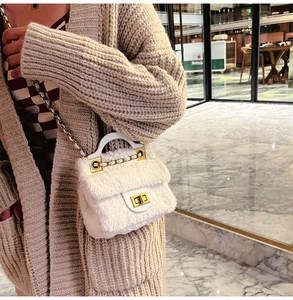 Détail d'un mini sac en fausse fourrure blanche avec fermoir doré et bandoulière chaîne
