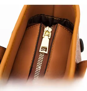 Detailed close-up of smooth gold zipper hardware and interior lining on leather bag