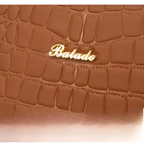 Macro shot of brown crocodile pattern leather with gold Balado logo hardware