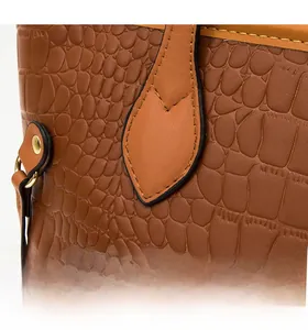 Close-up of brown crocodile texture leather bag showing reinforced stitching and gold rivets