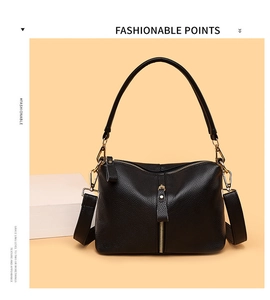 Detail of black pebbled leather handbag featuring gold hardware and removable strap