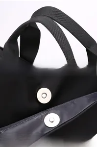 Detail of durable nylon webbing handles and magnetic metal closure on black laptop bag