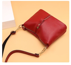 Detail of red pebbled leather texture and gold hardware on a chic crossbody bag