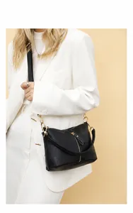 Model wearing a black lychee-textured leather crossbody bag with elegant gold zipper detail