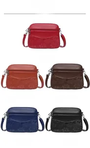 Detail showing five different colors of embossed floral crossbody bags with multiple zippers