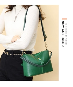 Close-up of green lychee leather handbag with adjustable strap and golden zippers