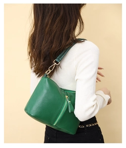 Close-up of green pebbled leather shoulder bag showing zipper detail and gold hardware