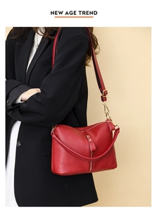 Detail of red litchi texture leather handbag with gold zipper and dual straps