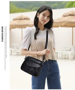Detail of black crossbody bag with embossed floral pattern and multiple zipper pockets