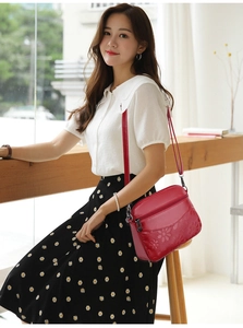 Detail of red embossed floral leather crossbody bag with adjustable strap and zip