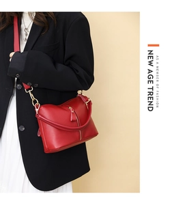 Detail of red pebbled leather shoulder bag with gold hardware on a stylish model