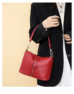 Detail of red lychee grain leather handbag featuring golden vertical zipper and metal accents
