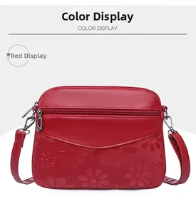 Detailed view of red crossbody bag featuring embossed floral texture and zipper compartments