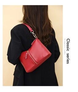 Rear view of a red leather shoulder bag with lychee texture on a model in a black blazer