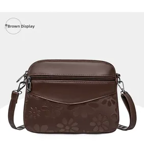 Detail of dark brown leather crossbody bag featuring embossed floral daisy patterns