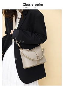 Close-up of beige leather handbag featuring litchi texture and gold metal hardware